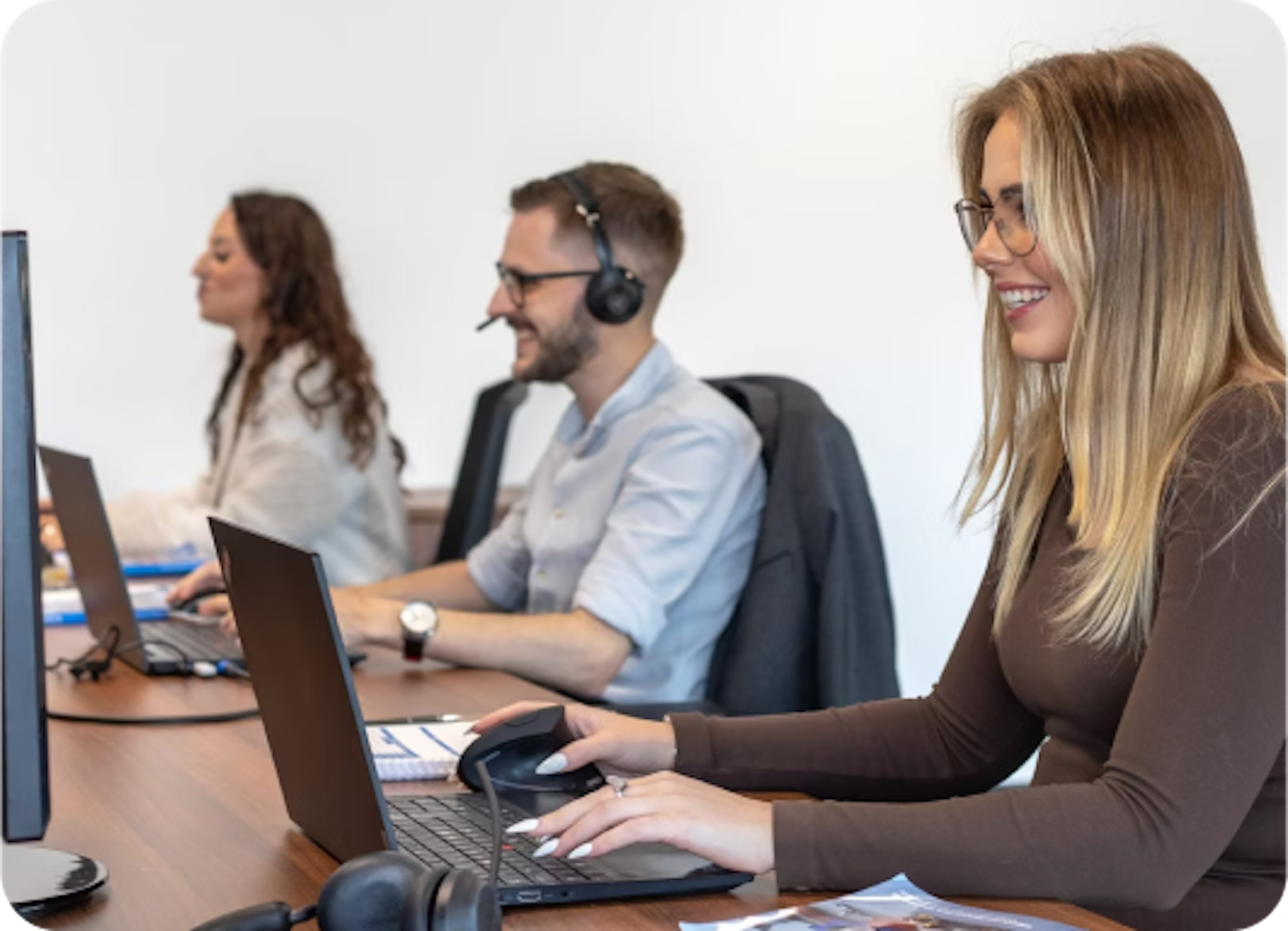 three people as customer services reps with headsets typing on laptop